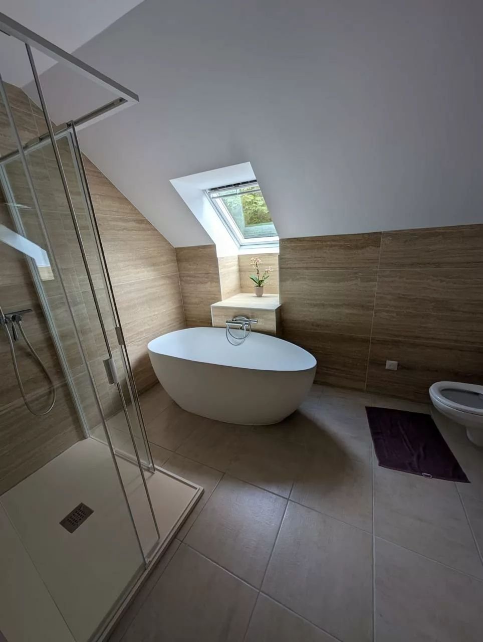 Salle de bains rénovée par AL Plomberie : baignoire îlot sous les combles